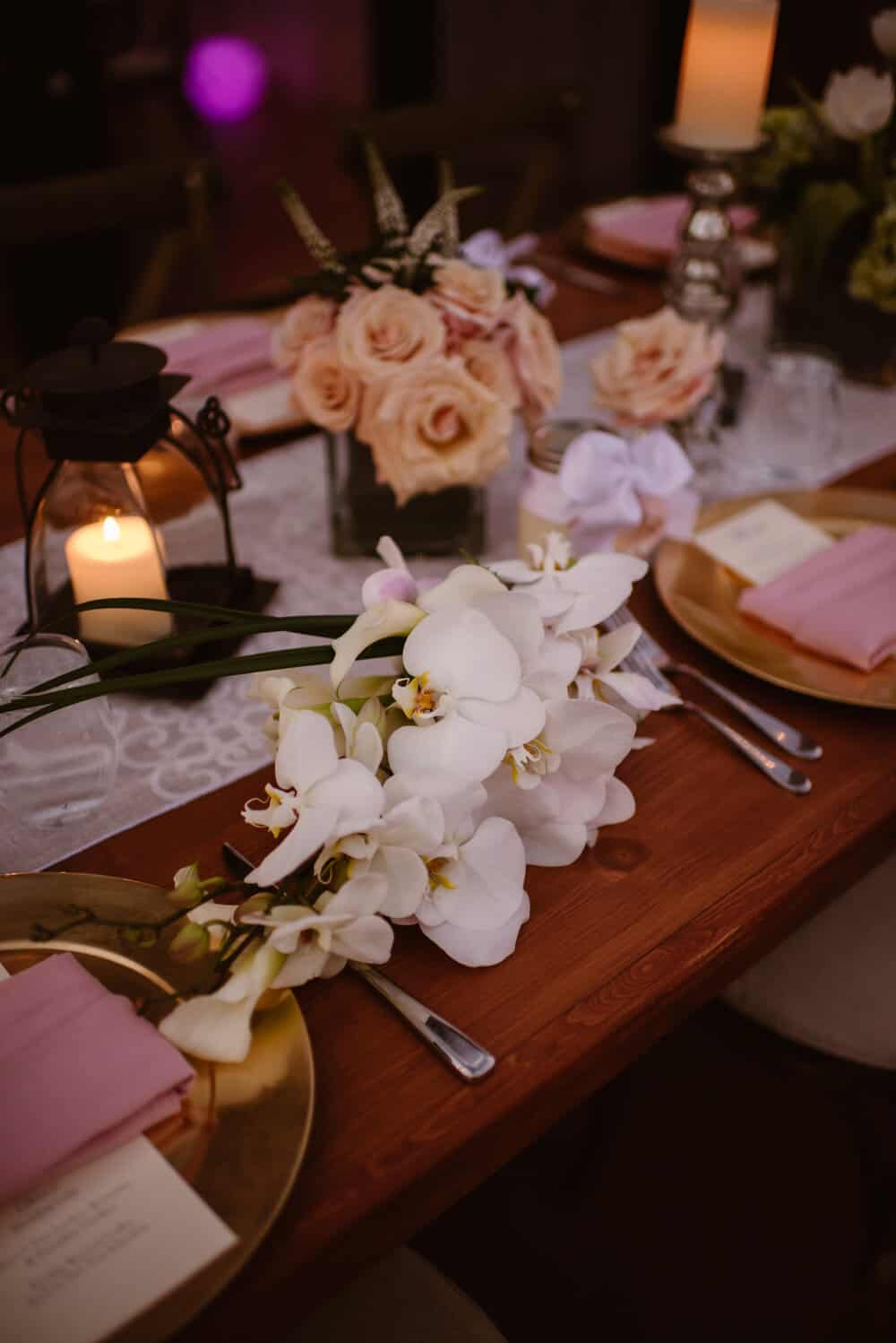A table layout with flowers, dinner plates and other items for a wedding dinner.
