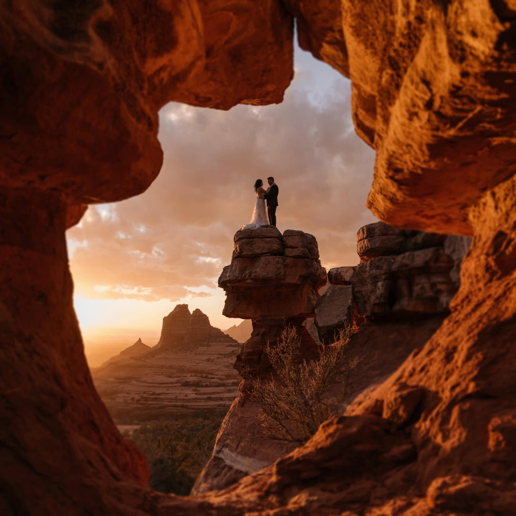 A couple stands on a rock ledge in Sedona at sunset on their elopement day.