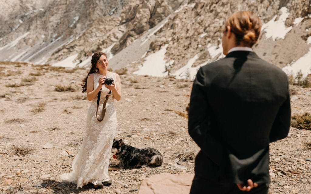 The bride smiles after taking a photo of the groom on his film camera.