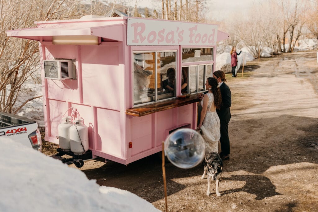 The bride and groom order their food from the food truck.