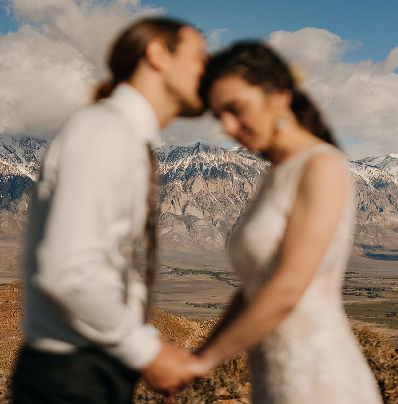 A person holding their partner's hands and kissing their head