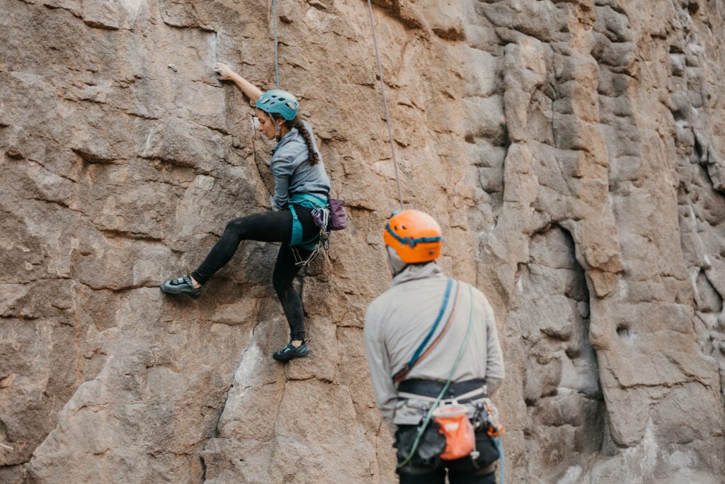 The bride tries a route as the groom belays her.