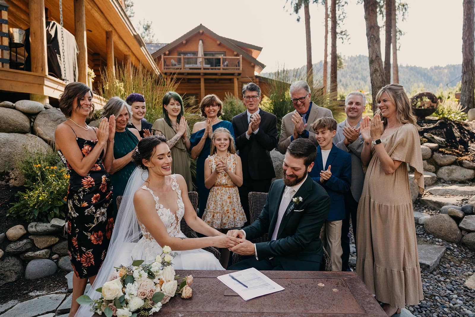 A bride and groom sign their marriage paperwork with their family around them.