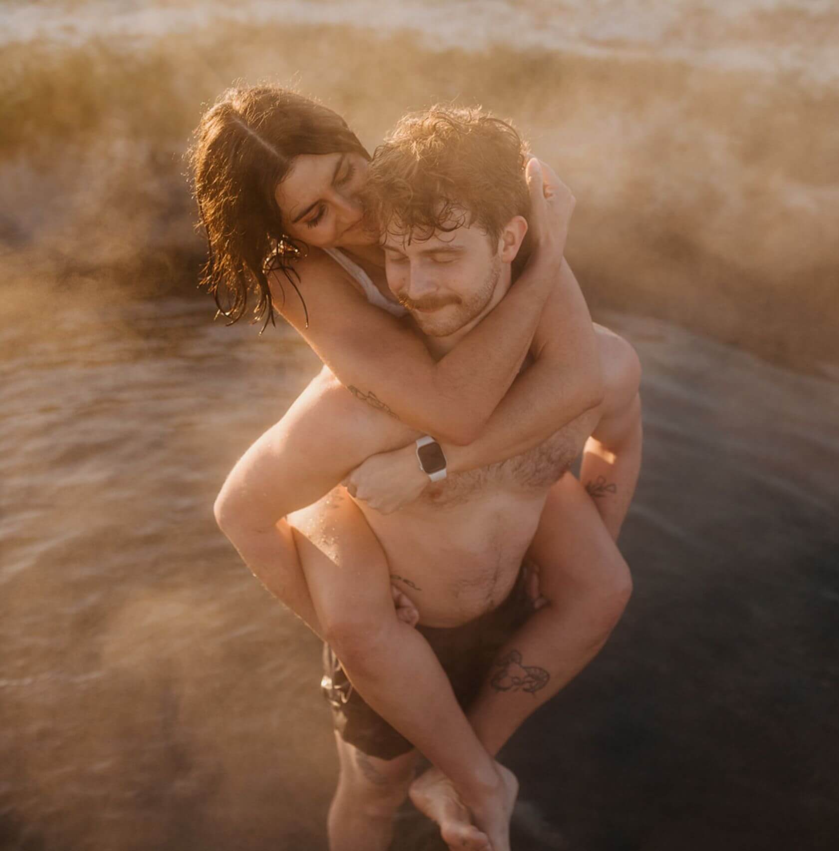 A person carrying their partner on their back in a hot spring