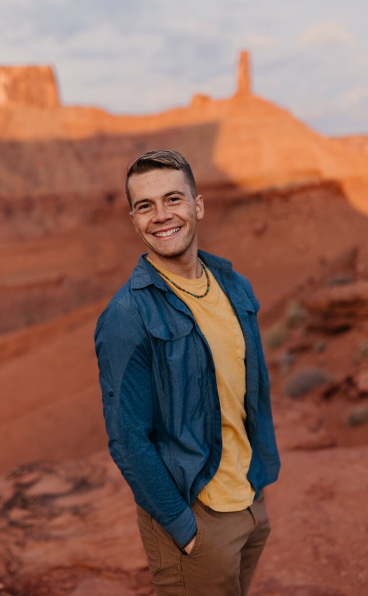 A person with their hands in their pockets smiling 
