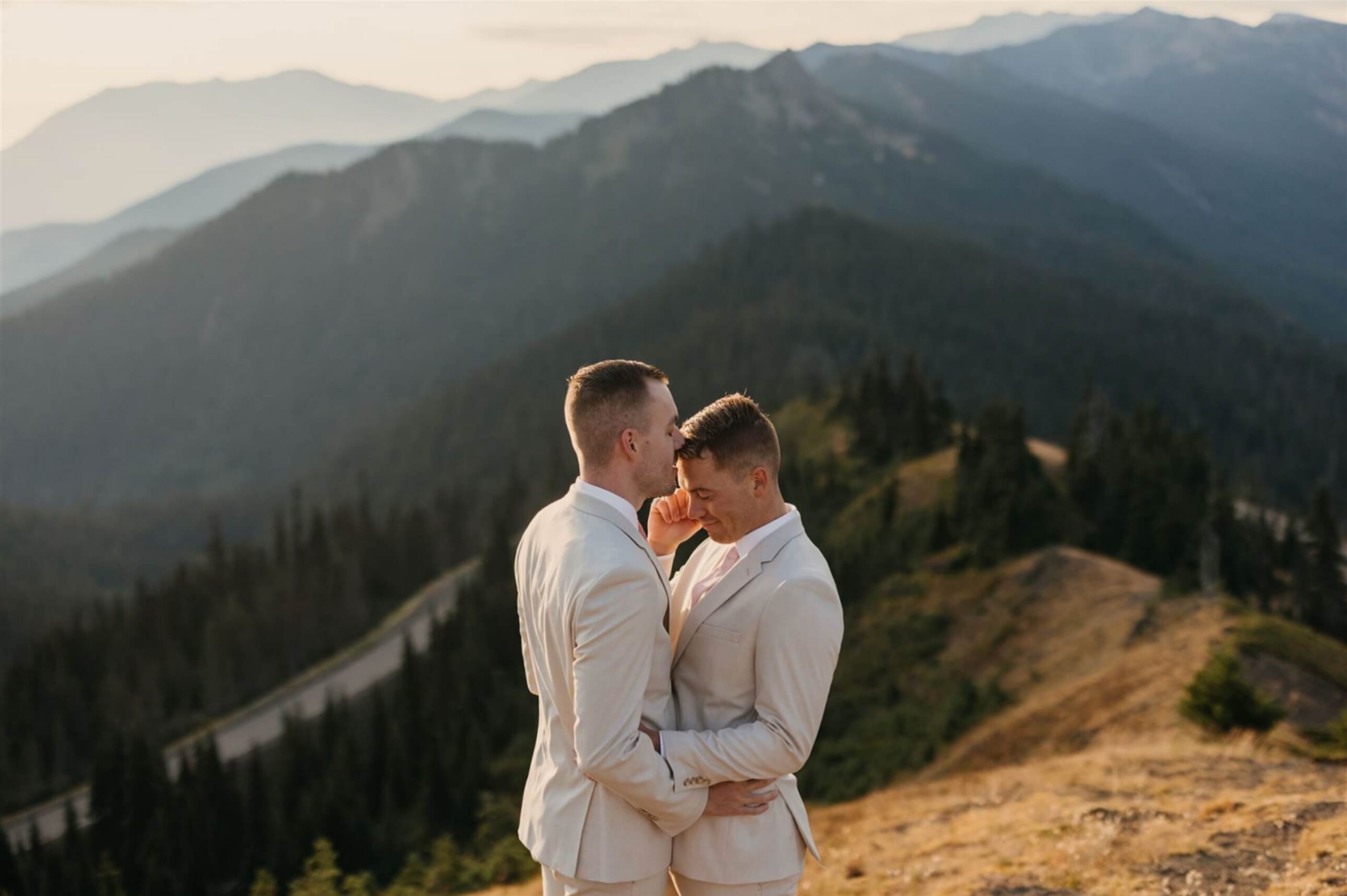 A person about to kiss their partner's cheek as they hold each other's waists. 