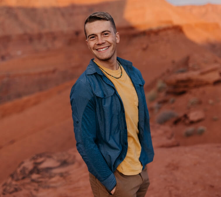 A person smiling with their hands in their pockets 