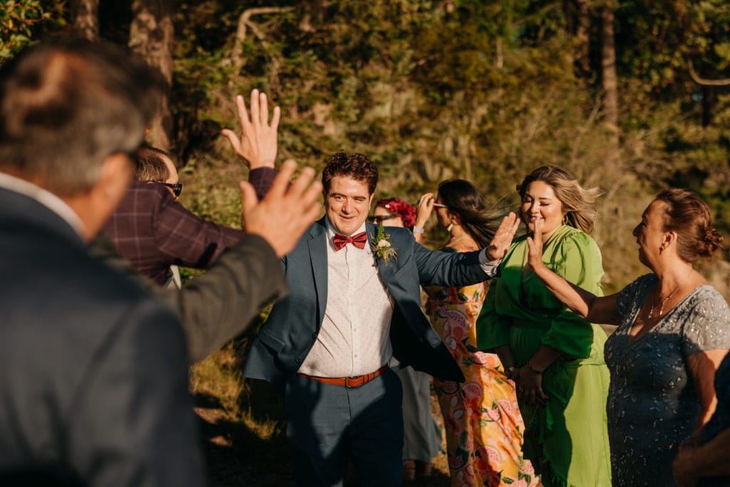 A groom giving high fives as he walks down the aisle.