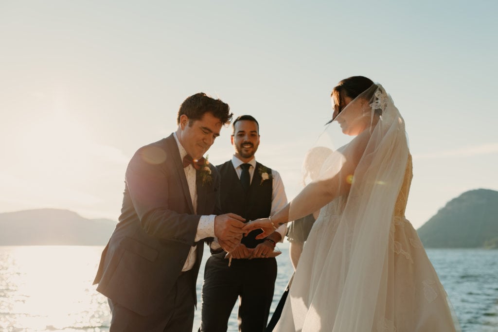 A groom places a wedding ring onto his brides finger.