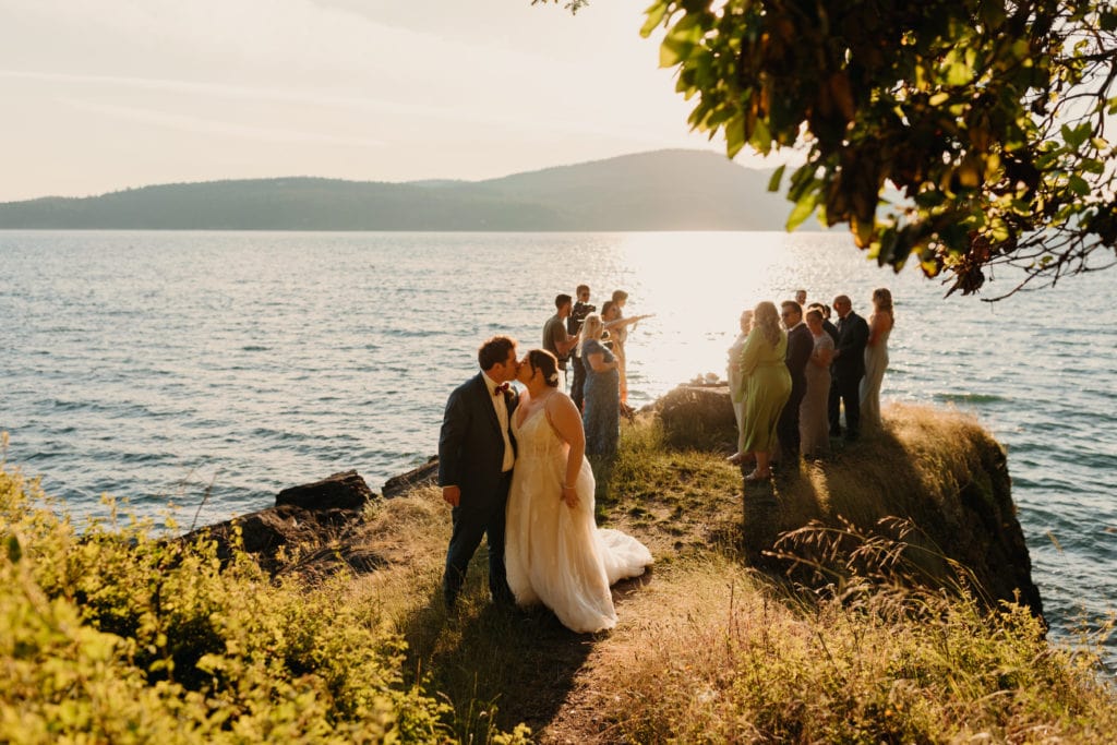A couple shares a kiss after their ceremony as their family watches.