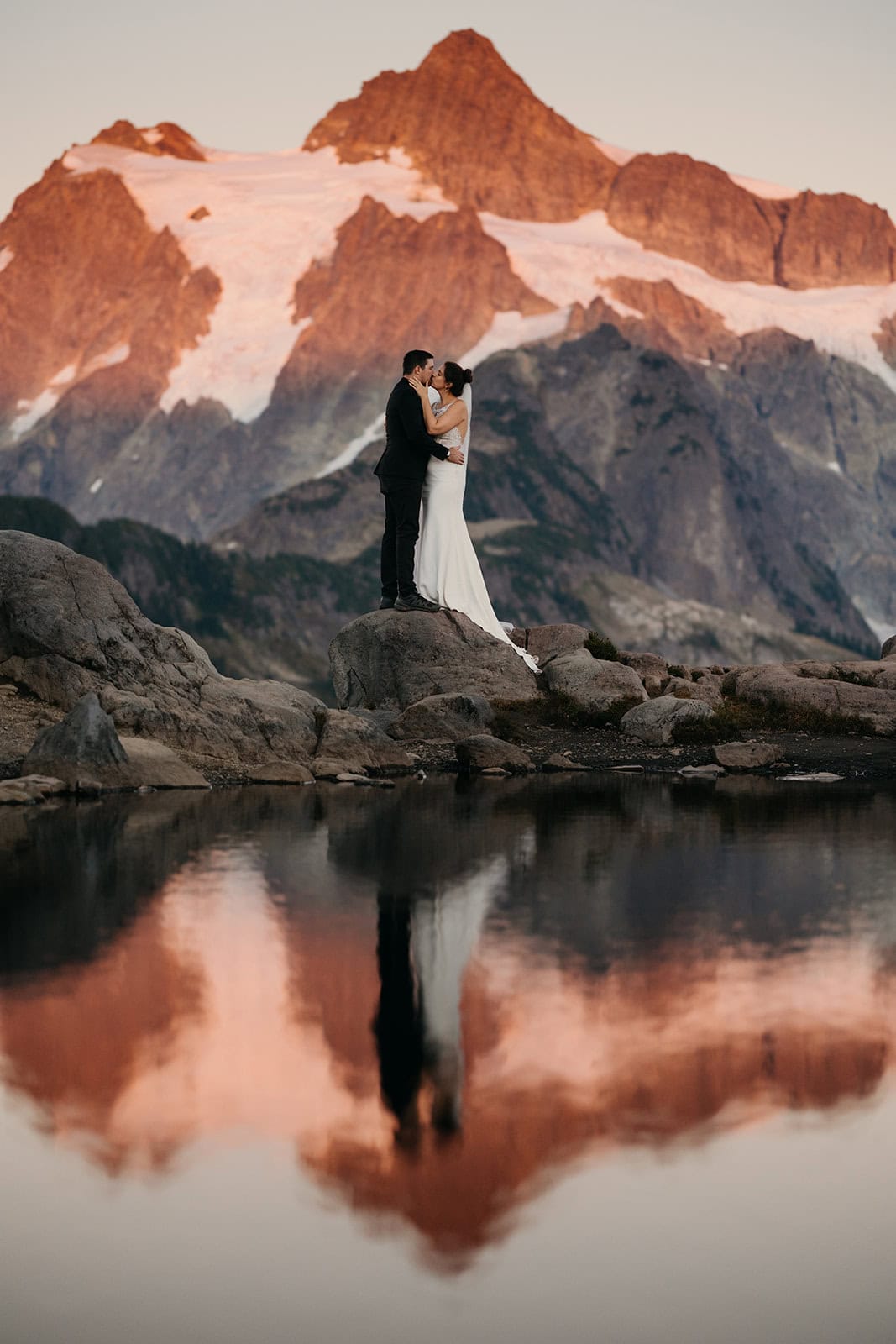 A couple shares a romantic kiss in the mountains alpine glow. 