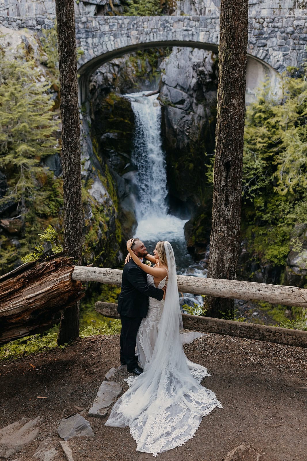 A couple holds each other near a waterfall in Mt Rainier.