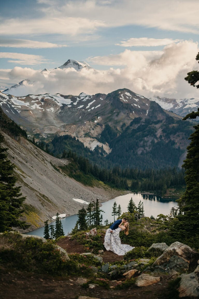 A couple shares a passionate dip kiss in the mountains at dusk.