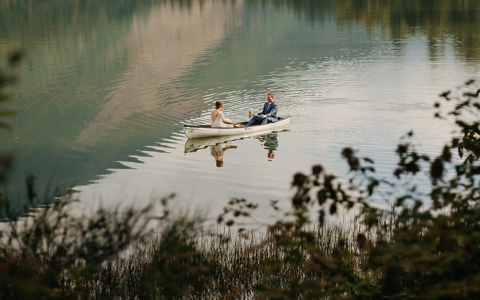 A couple canoes in a lake together after becoming married.