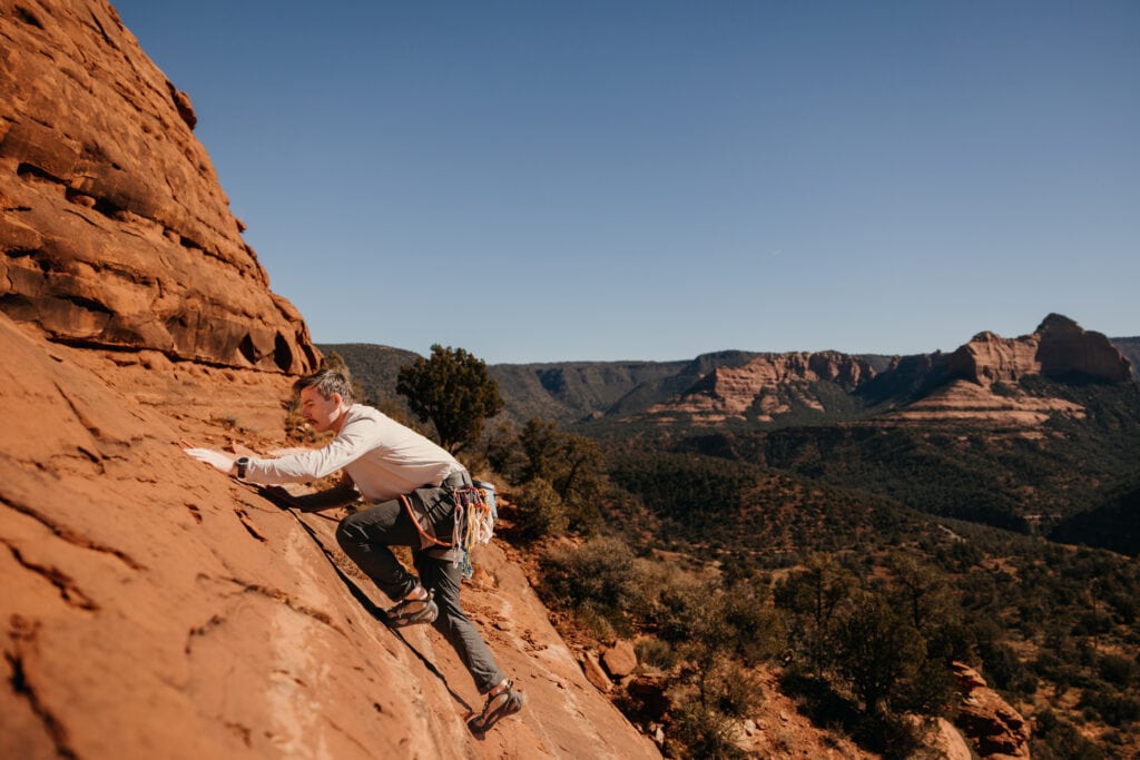 A man climbs up a slab pitch in the red rocks of Sedona arizona