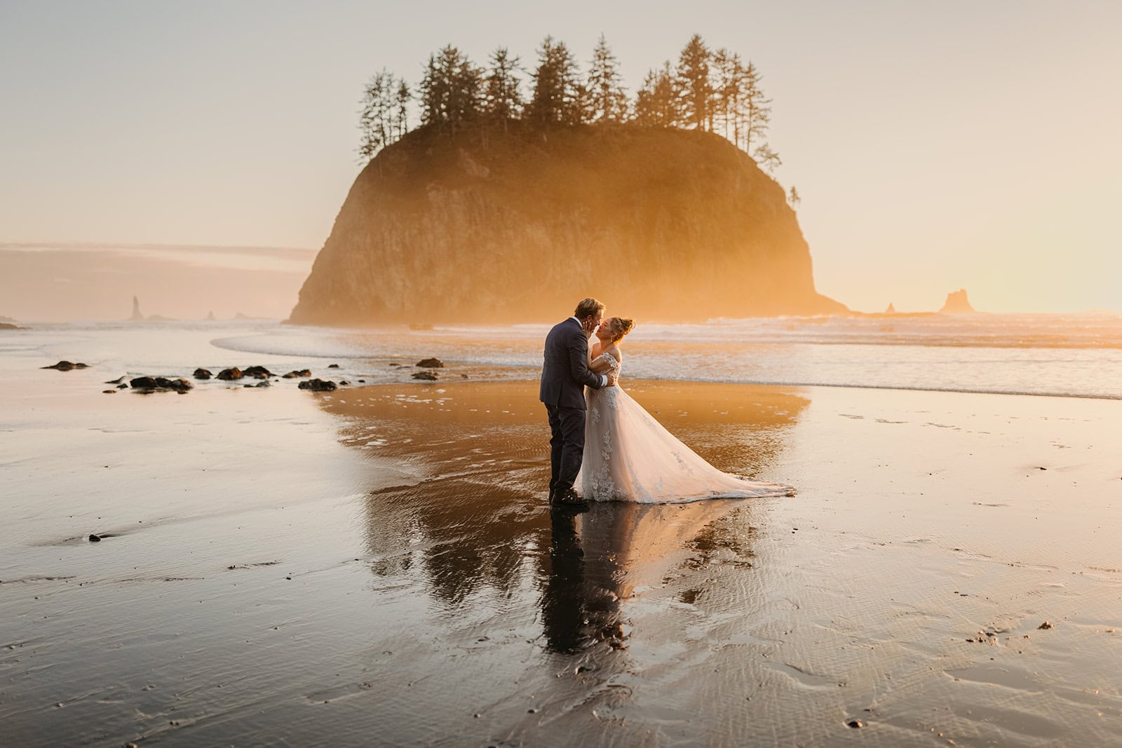 A couple shares a kiss in the sunset light on the coast.