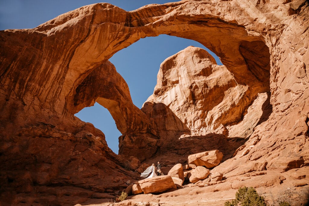 A bride and groom standing together in the windows section of arches national park