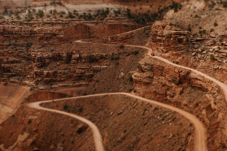 A couple drives Shafter Trail road in Canyonlands National Park.