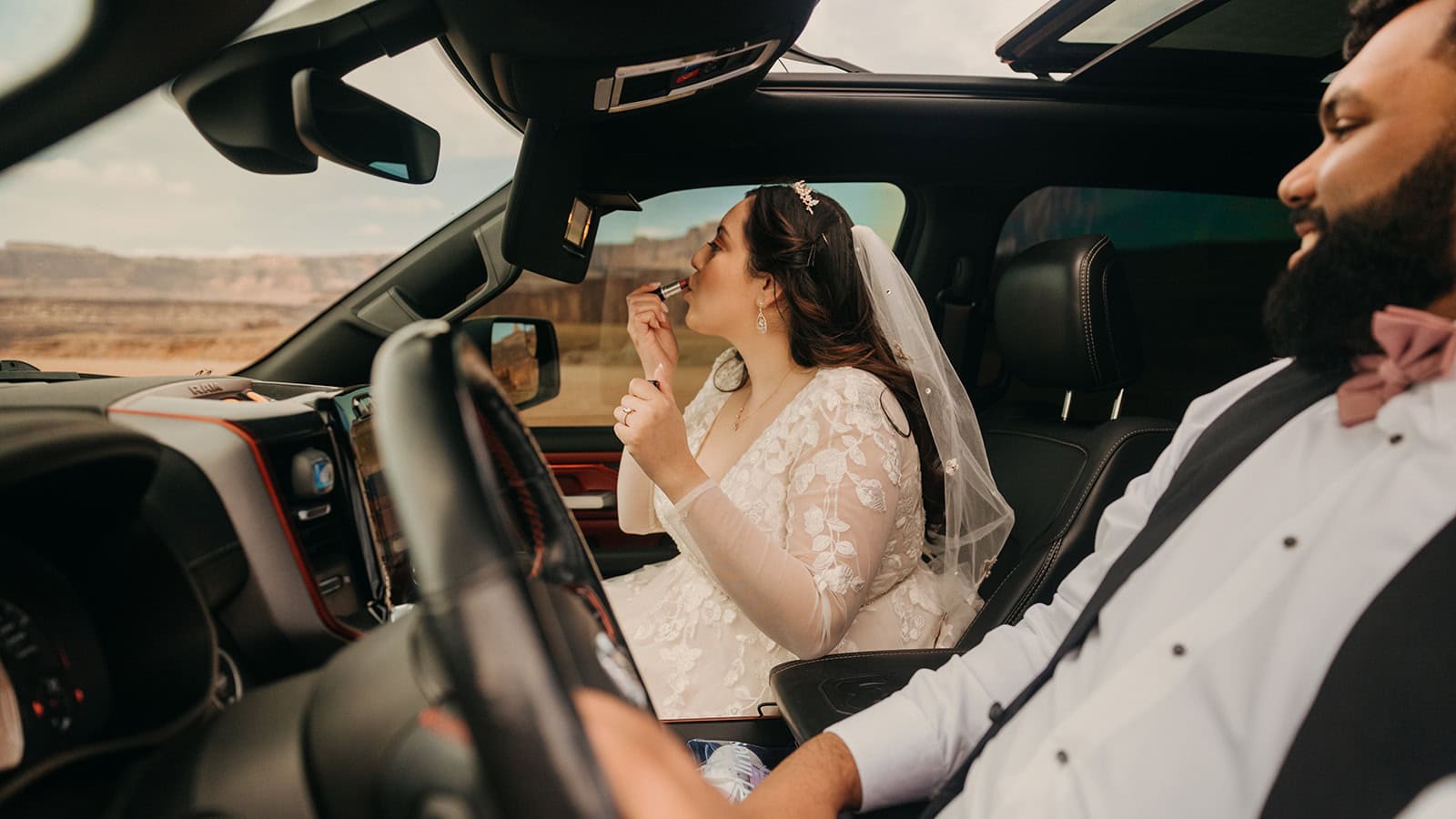 A bride touches up her lipstick in the truck.