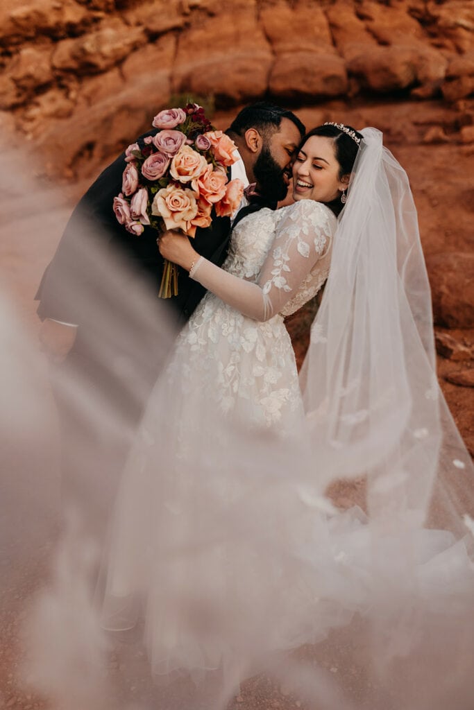 The groom kisses the bride on the cheek.