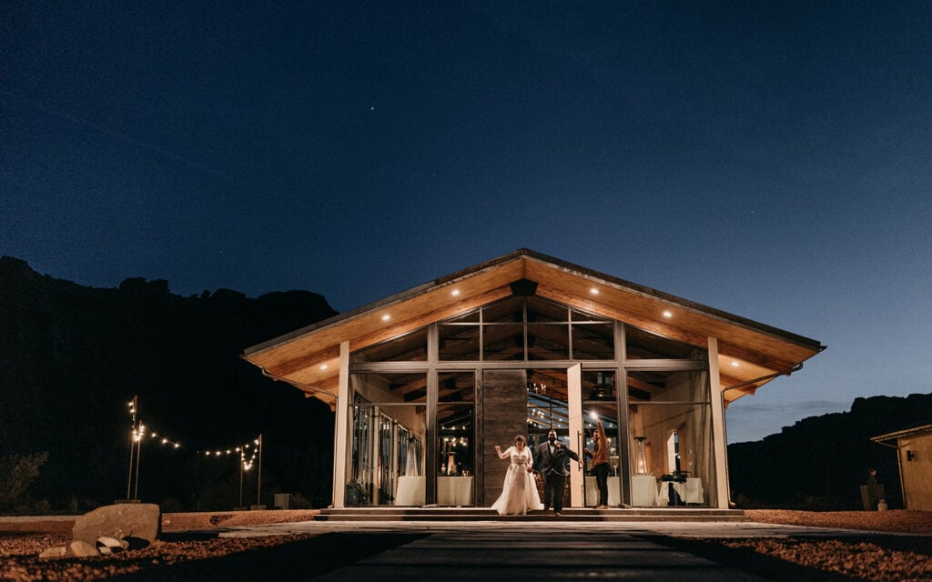 The bride and groom exit red earth venue at night.