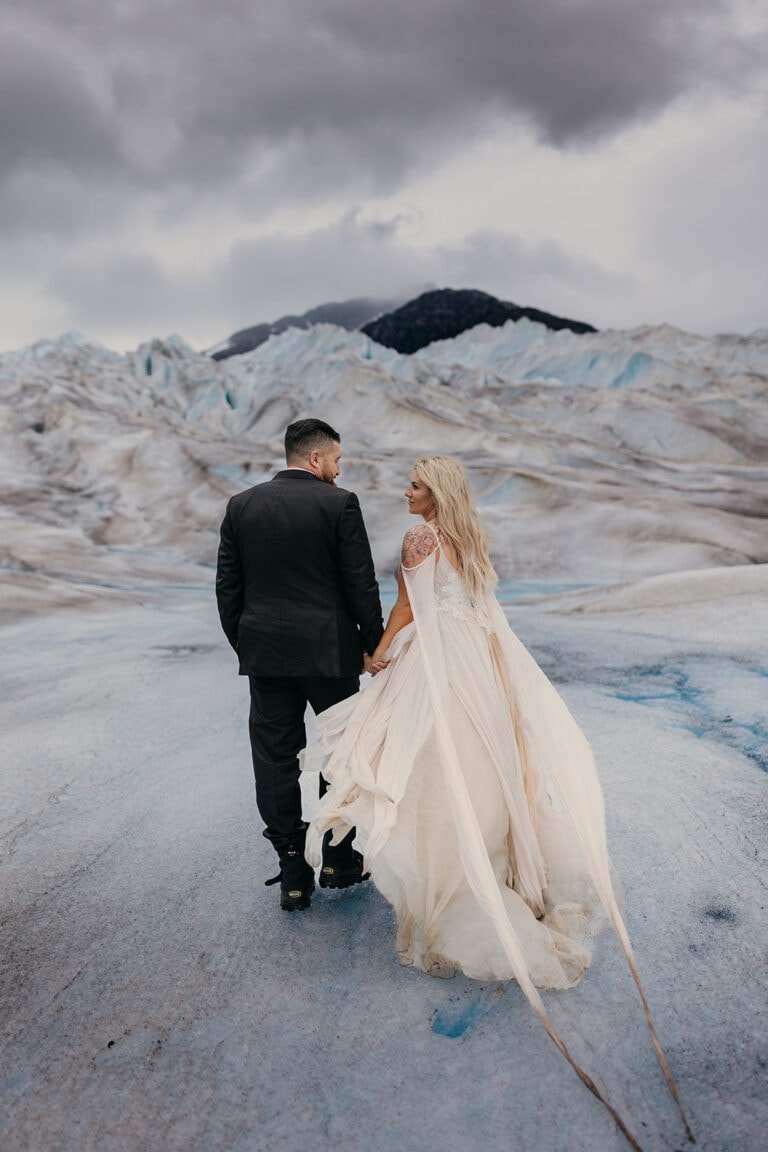 A couple holds hands and walks across Hubert glacier in Juneau, Alaska.