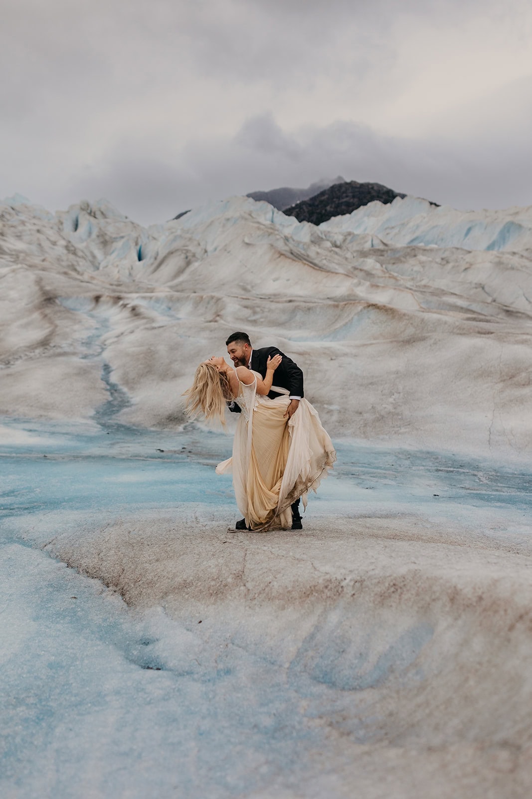 A couple shares a passionate dip together on their wedding day on the glacier.