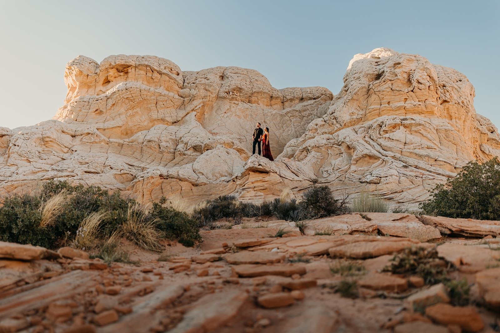 A couple stands within a massive color rock formation.