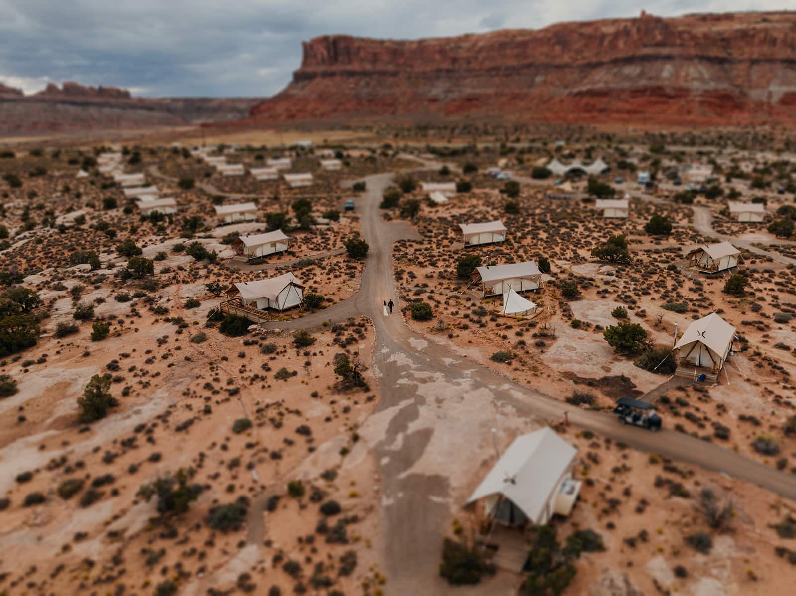 A bride and groom walking together at Under Canvas from the perspective of a drone.