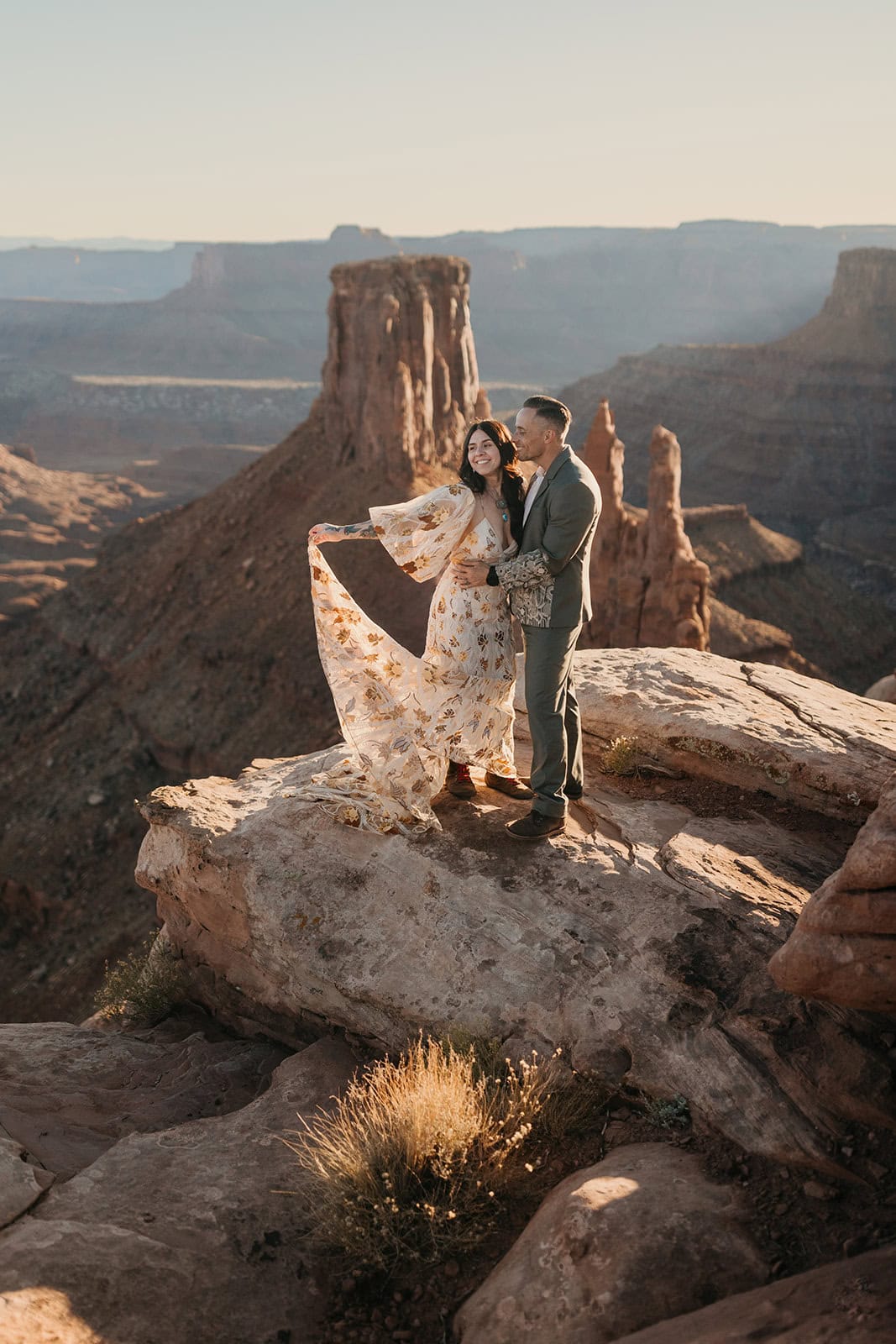 A bride plays with her elopement dress in the sunlight.