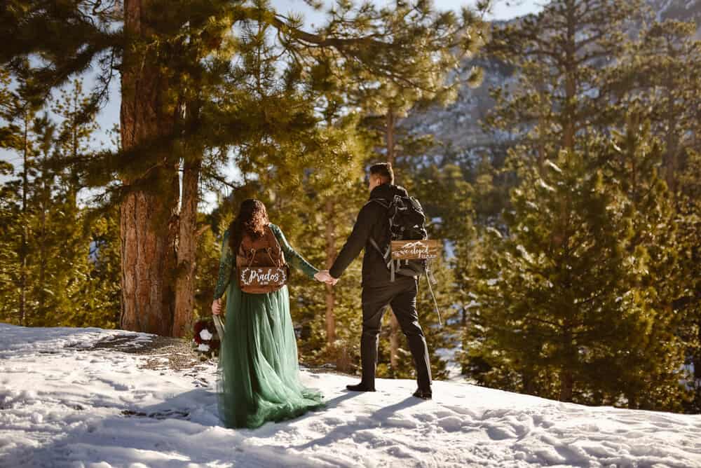 A couple holds hands walking in the snow.