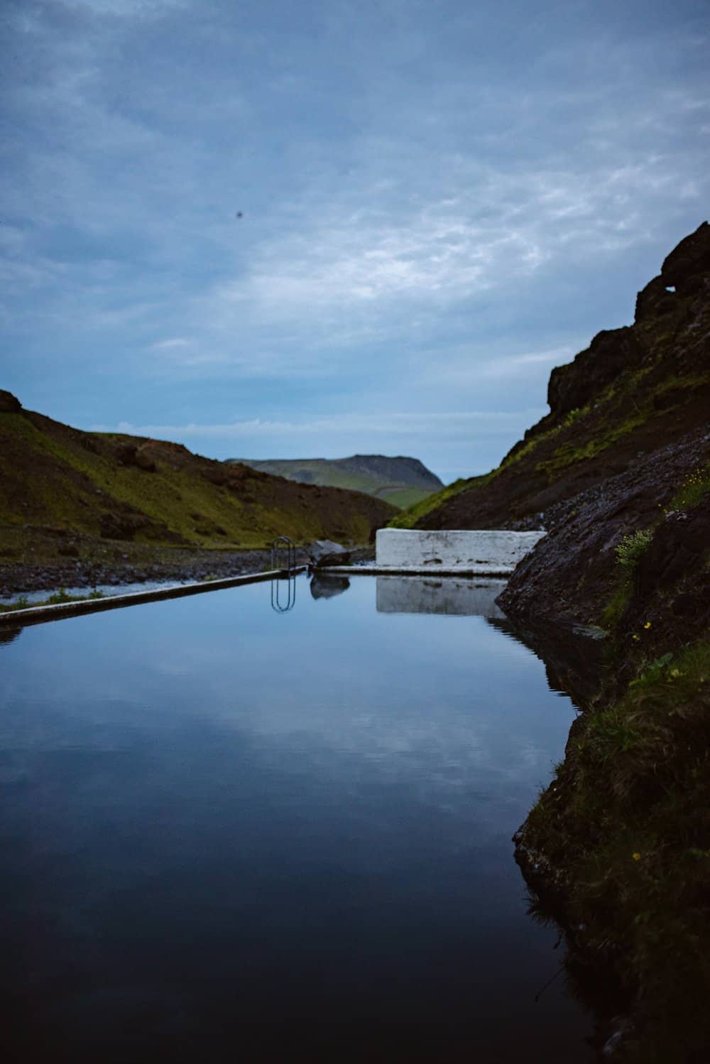 Seljavallalaug in summer looking out towards the clouds and view.
