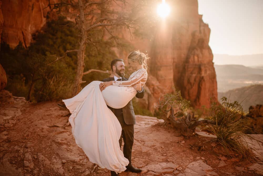 A groom hold his bride as they smile and laugh together. 