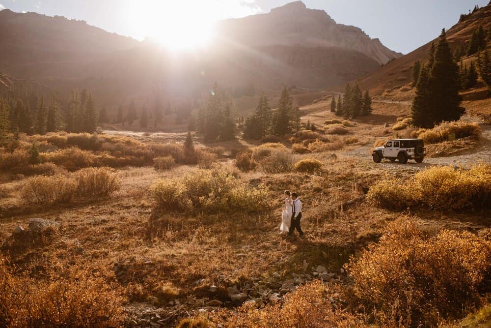 A couple walks down a path surrounded by Colorado mountains.