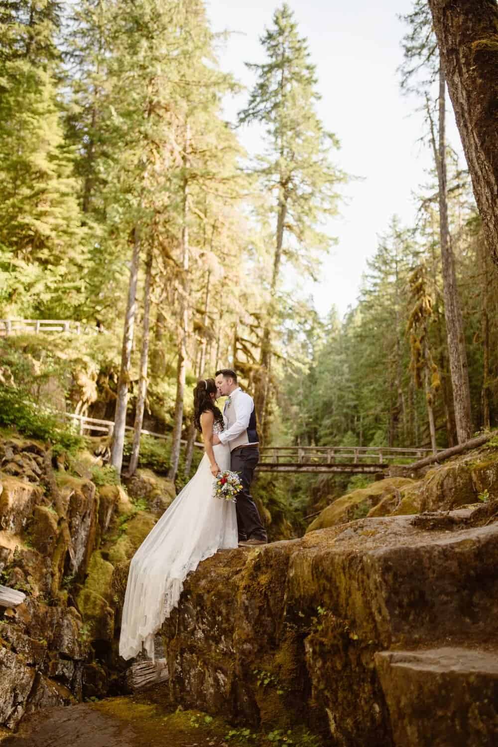 A couple shares a kiss in the forest.