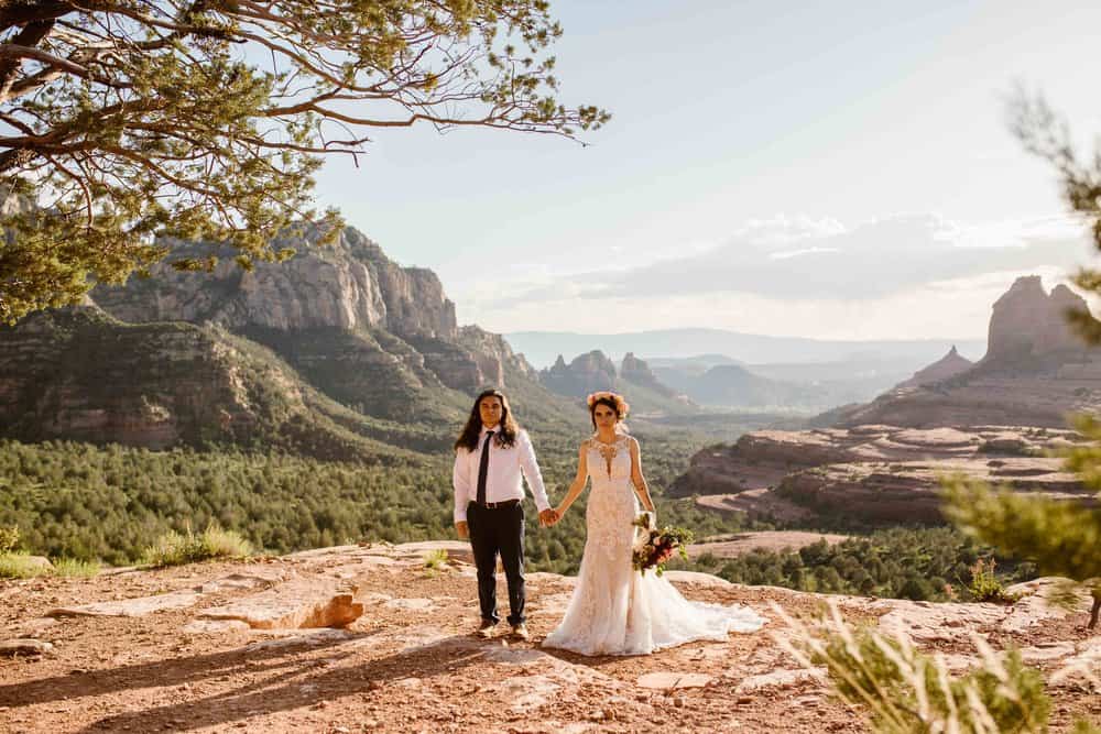 A bride and groom hold hands and look towards the camera.