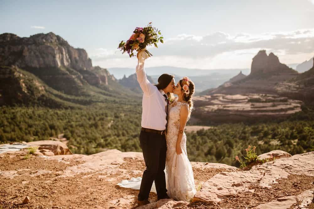 A groom lifts the flowers as he kisses his bride.