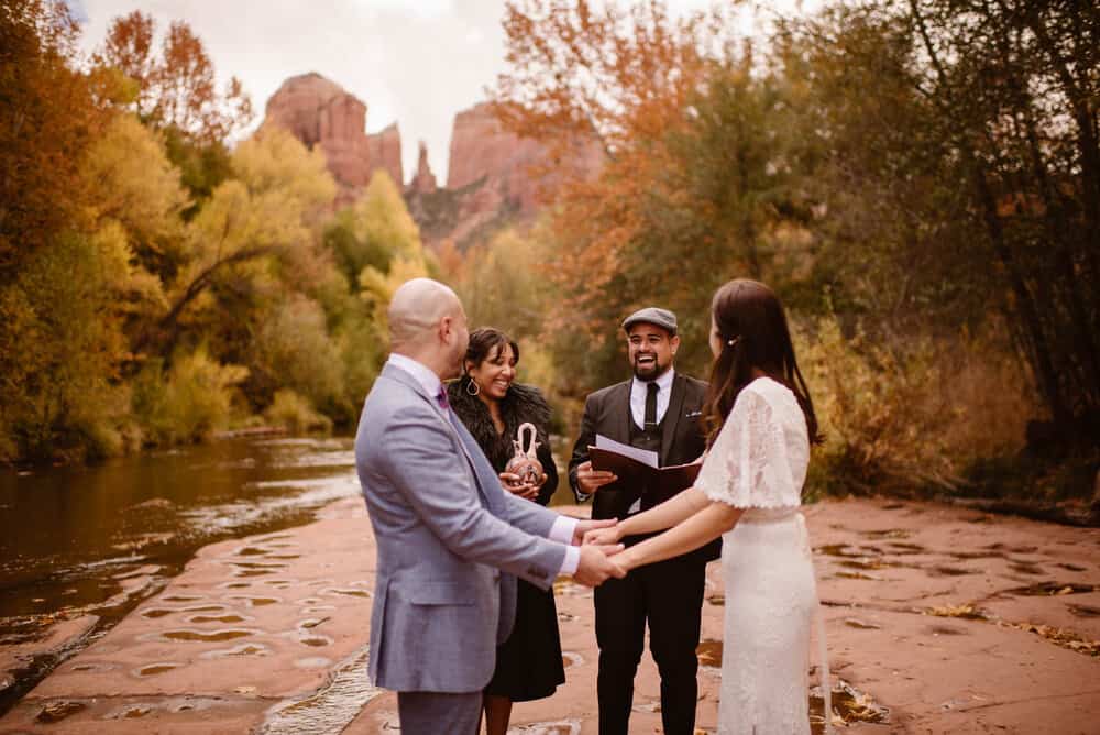 A man and woman perform the couples elopement ceremony by a river.