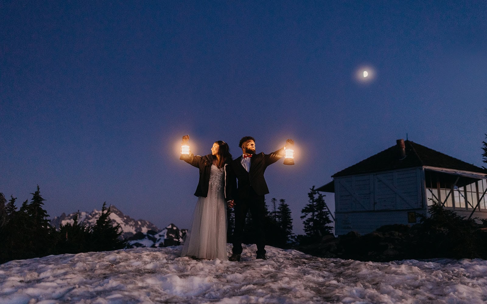 A couple hikes through the night with lanterns in a snowy mountain scene.
