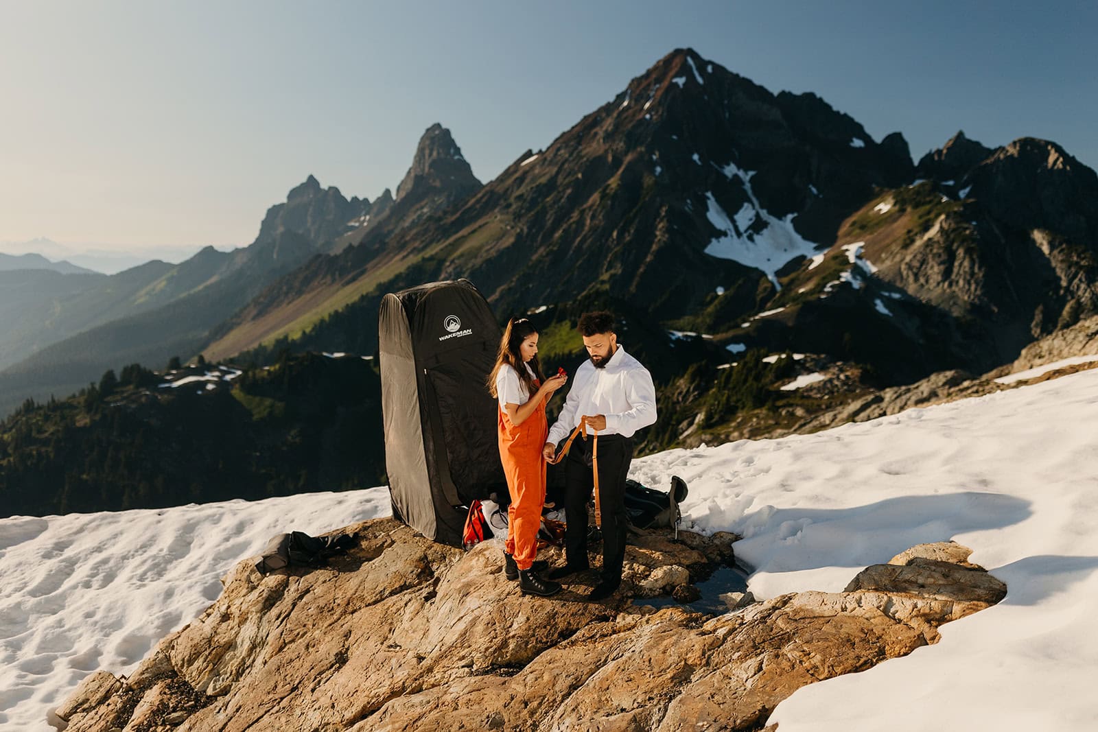 A bride and groom get changed for their elopement on top of a mountain.