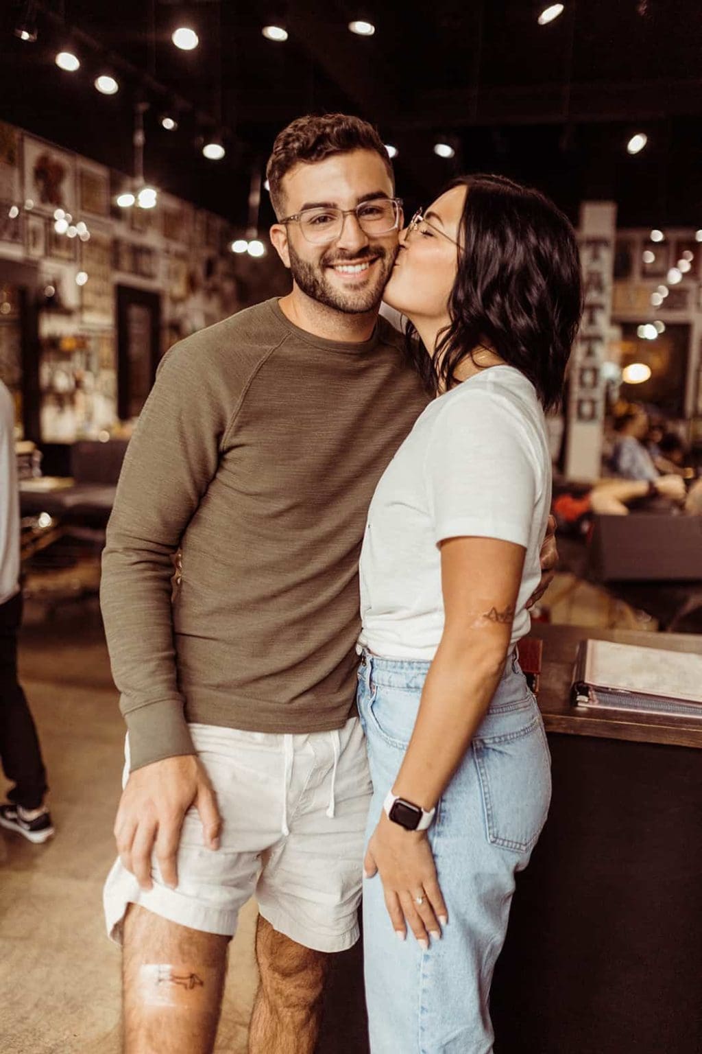 An engaged couple posing for a picture after getting matching tattoos together
