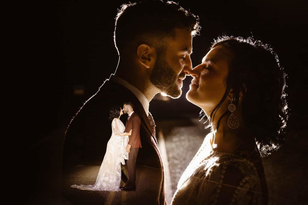 The bride and groom stand close together in the light of a jeep in this double exposure image
