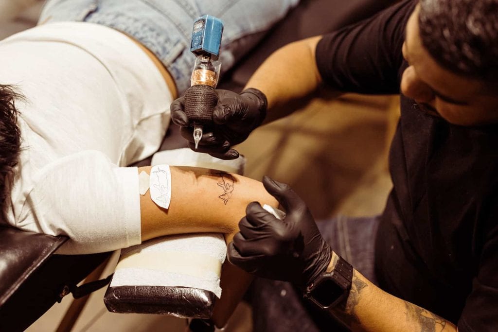 A bride gets a tattoo of her dog on the back of her arm.