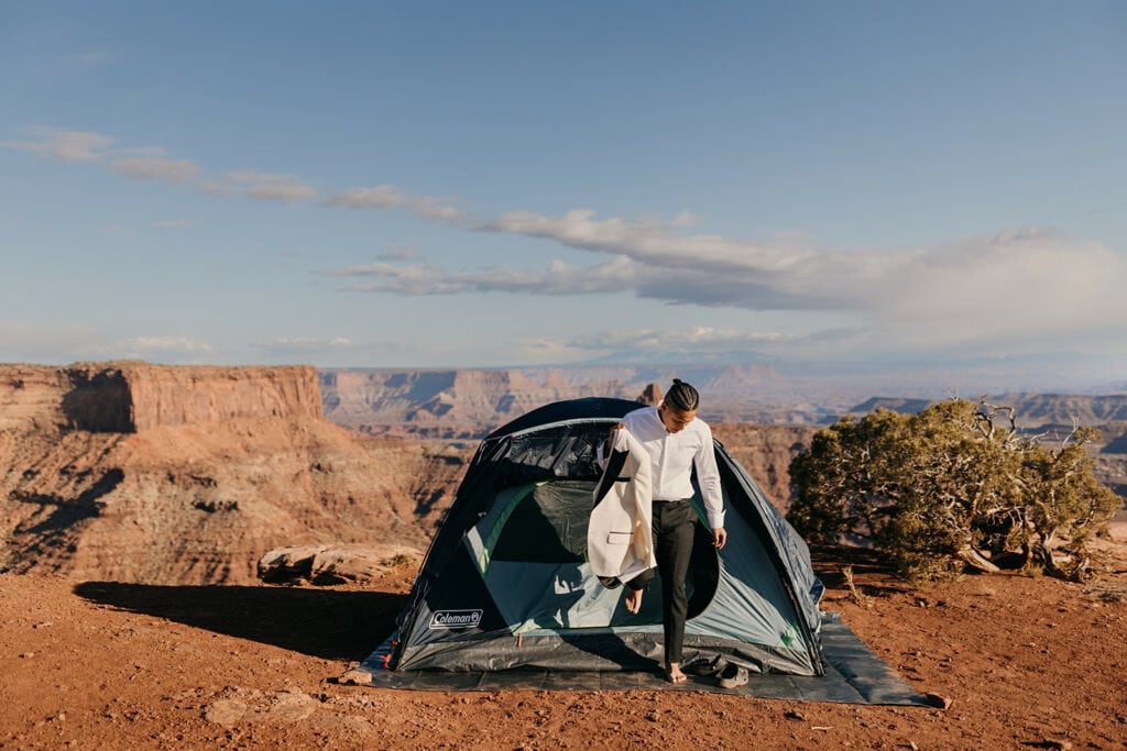 The groom exits the tent to finish getting dressed. 