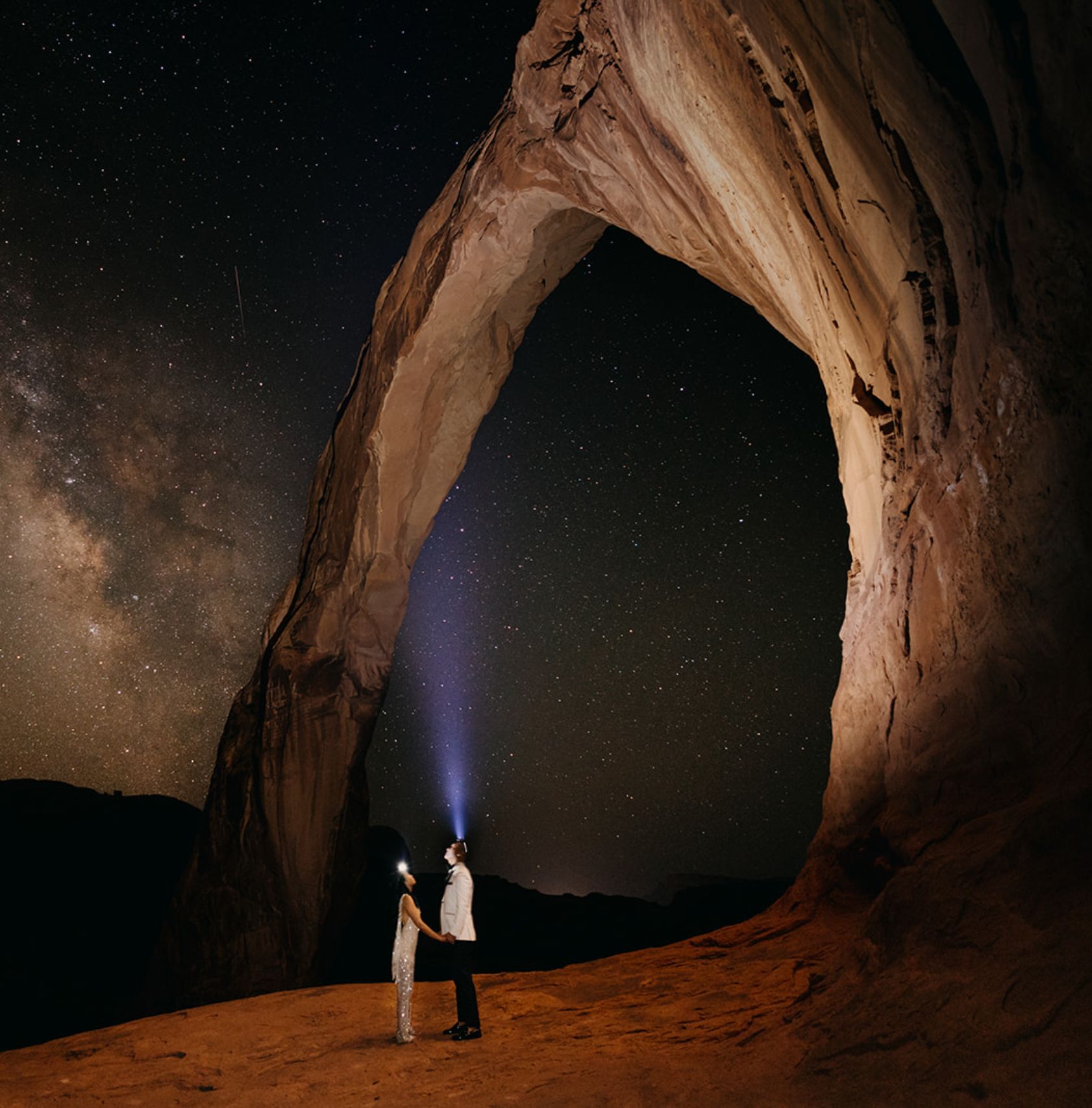 A couple standing in the middle of an red rock arch on their wedding day