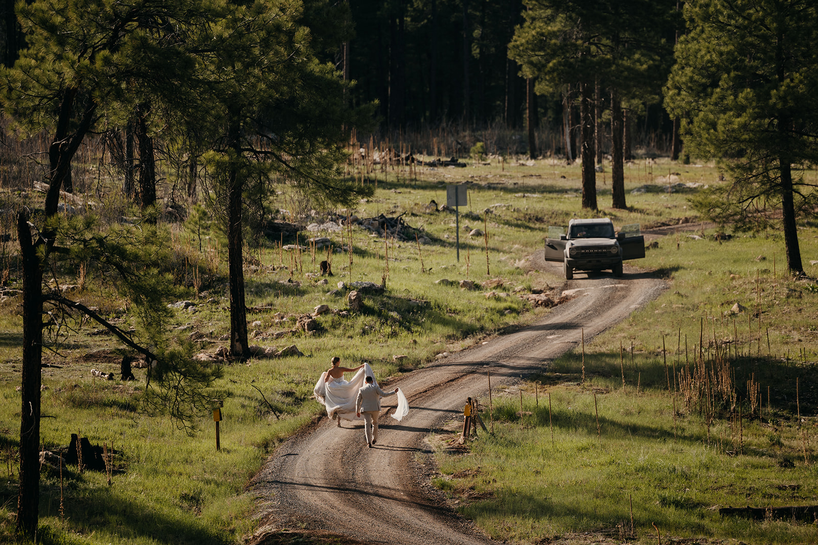 A couple runs up a forest service road surrounded by ponderosa pines in Flagstaff.