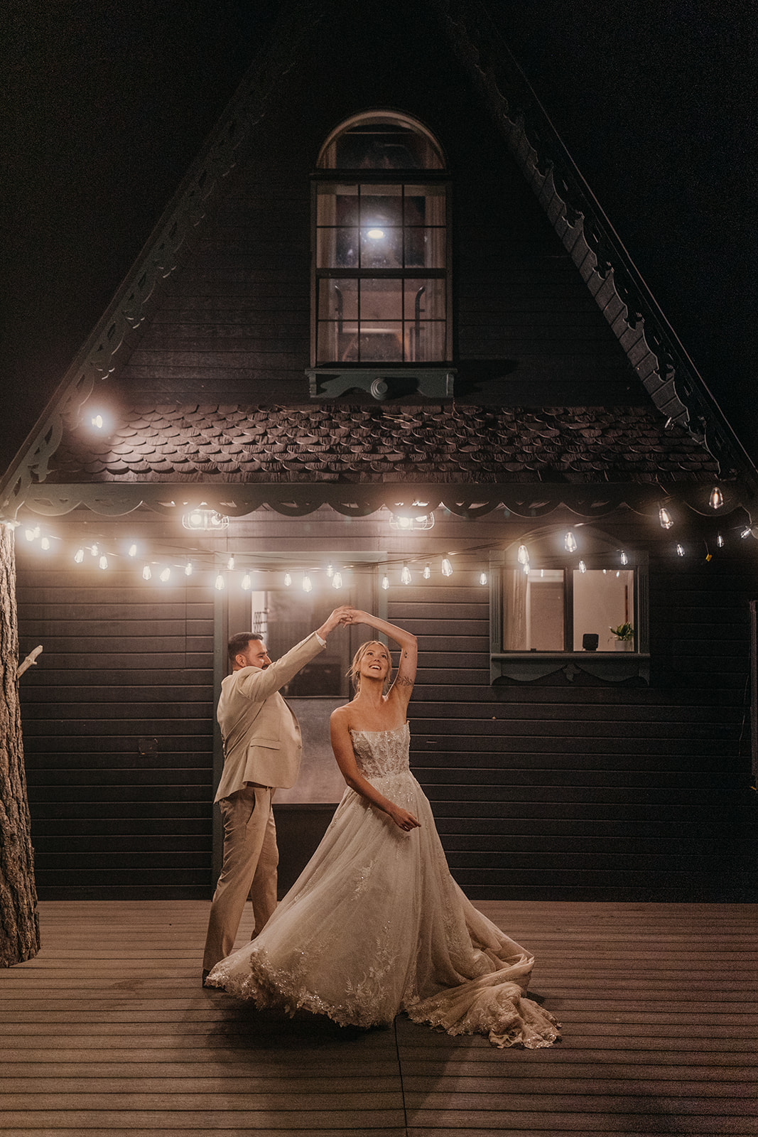 A groom spins his bride under the twinkle lights at an Airbnb.