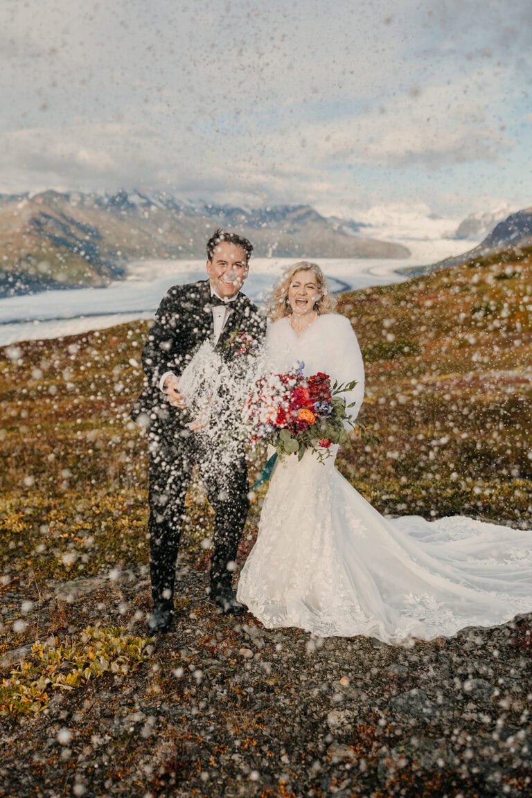 A couple sprays Champagne to celebrate their elopement in Alaska.