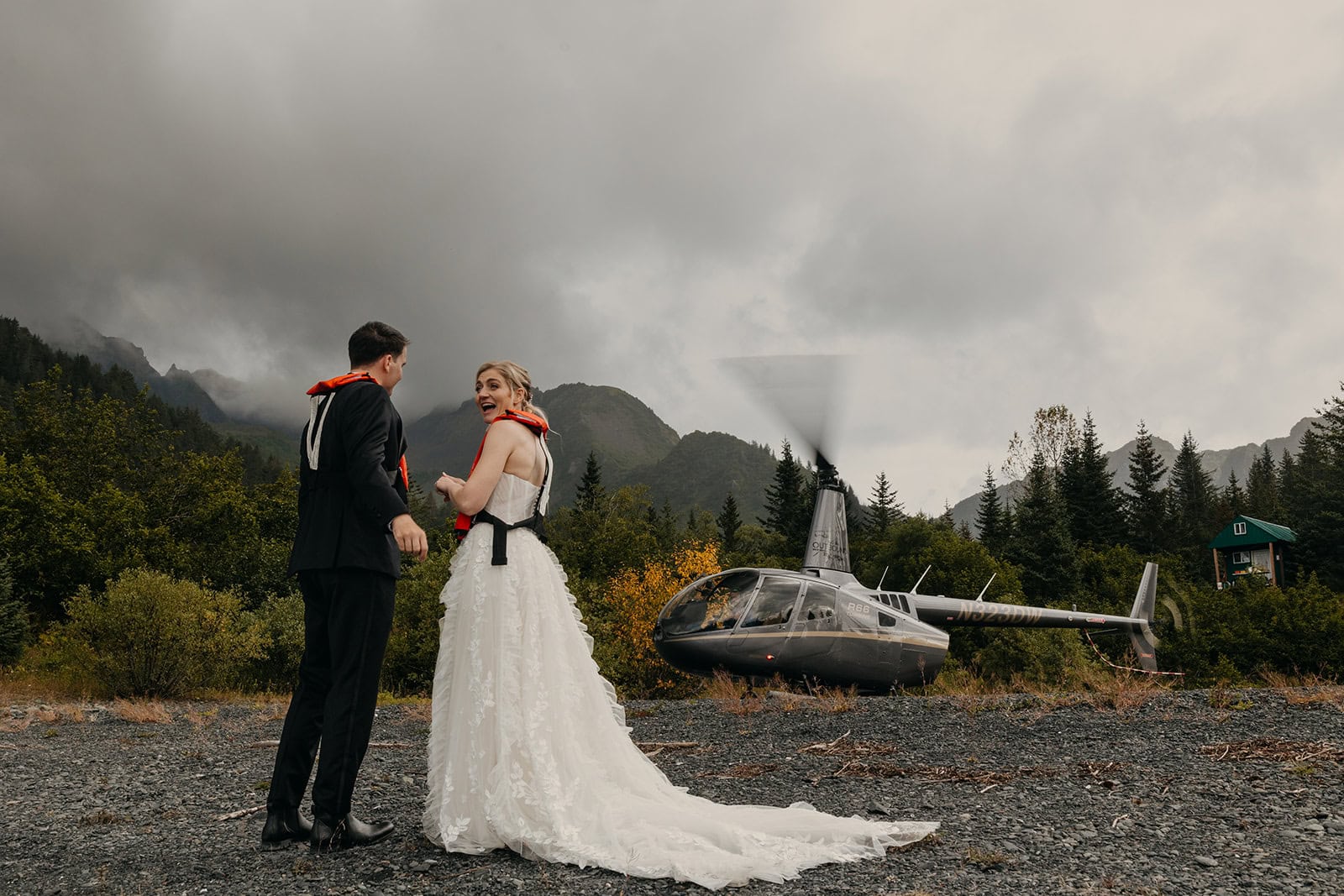 A couple waits for a helicopter to power down so they can board the aircraft.