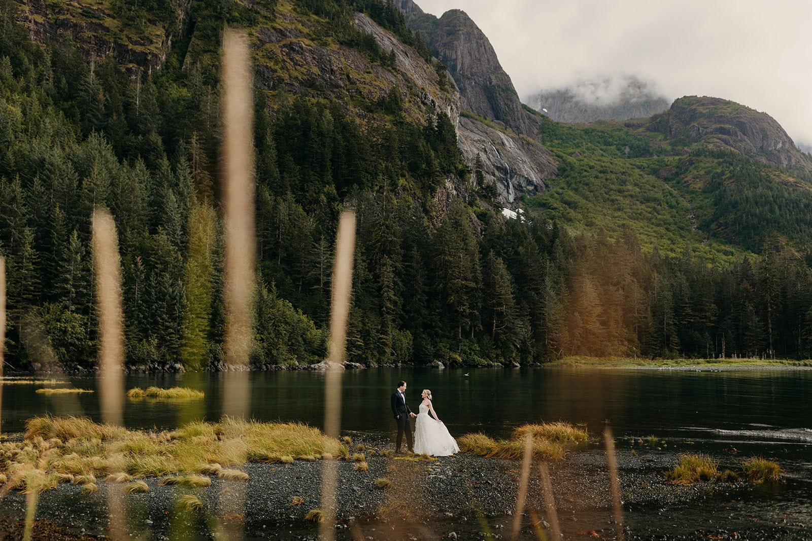 A couple stands together on a remote beach in Alaska after a helicopter dropped them off. 